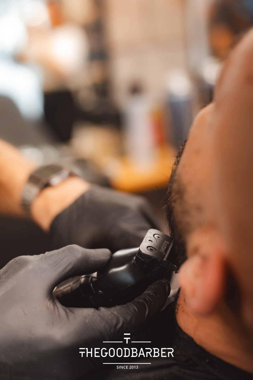 Barbero perfilando barba con máquina eléctrica en The Good Barber